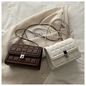 Detail of quilted square crossbody bags in brown and white with chain straps