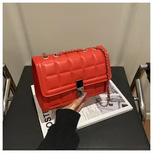 Close-up of red quilted crossbody bag with silver rotating lock and metal chain strap