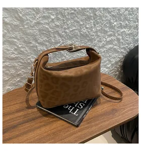 Detail shot of leopard embossed pattern and golden buckle on brown crossbody bag