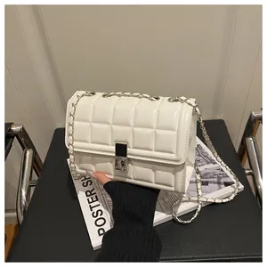 Detail of white quilted crossbody bag with silver chain strap and metal lock closure
