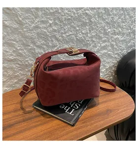 Close-up of deep red leopard print crossbody bag with gold snap button on a wooden table