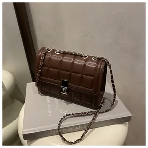Detail of dark brown quilted square bag with silver chain strap and metal clasp