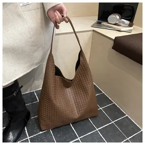 Gros plan détaillé sur la texture en cuir tressé marron foncé d'un élégant sac à bandoulière