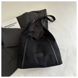 Detail of minimalist matte black shoulder bag showing textured material and side trim