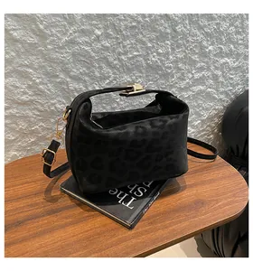 Detail of black leopard embossed handbag with gold metal clasp on a wooden table