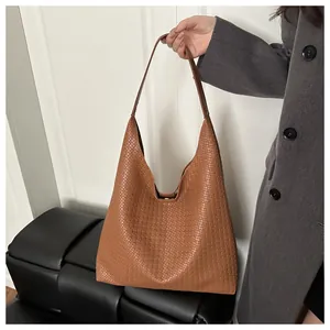 Gros plan sur la texture en cuir tressé marron et la finition artisanale du cabas