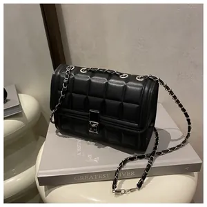 Detailed view of black quilted chain bag with silver square lock on a minimalist background
