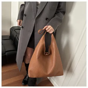 Détail d'un sac à bandoulière tressé marron présentant une silhouette triangulaire moderne