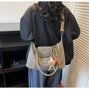 Model view of grey-green crossbody bag with geometric woven strap and plush charms