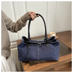 Detail of dark blue denim tote bag with leather straps and silver buckle accent