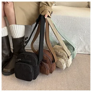 Détail du sac bandoulière en velours côtelé avec double fermeture éclair en quatre couleurs