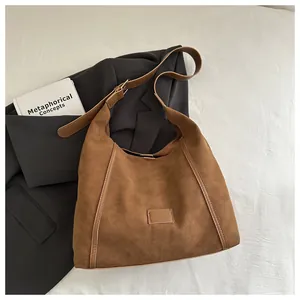 Detail of a brown suede tote bag featuring smooth leather trim and premium stitching