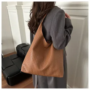 Sac à bandoulière en cuir tressé marron montrant la grande capacité et le style sur modèle