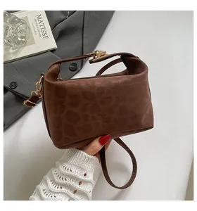 Detail shot of vintage leopard print texture and gold lock hardware on a brown handbag