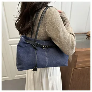 Detail of dark blue denim tote bag with black leather straps and white contrast stitching