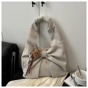 Détail du sac bandoulière en velours côtelé beige avec nœud et charms ours en peluche