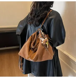 Detail of vintage brown oversized hobo bag with white stitching and plush bear charm