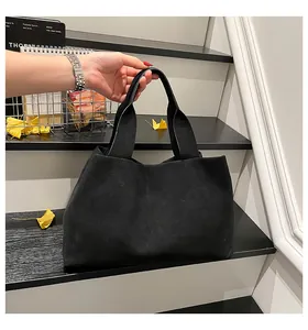 Minimalist black tote bag in matte suede texture shown in a creative lifestyle setting