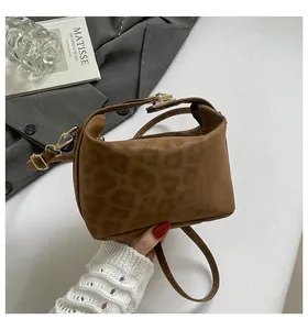 Macro view of leopard print texture and metal lock on brown suede crossbody bag