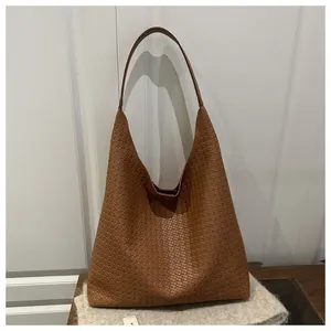 Détail macro de la texture en cuir PU tressé marron sur un grand sac hobo porté épaule