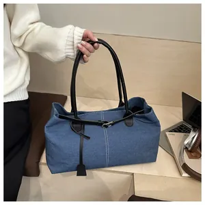 Close-up of blue denim tote bag featuring white stitching and premium black leather handles