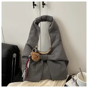Détail du sac bandoulière en velours côtelé gris avec nœud et breloque ours