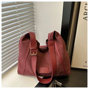 Detail of burgundy suede hobo bag with adjustable leather strap and gold buckle