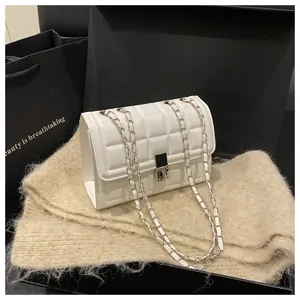 Close-up of white quilted square crossbody bag with silver chain on beige knit scarf