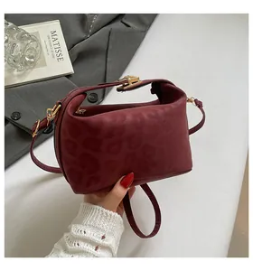 Detail of burgundy leopard embossed crossbody bag with gold hardware and stylish clasp