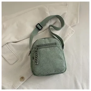 Détail du sac bandoulière en velours côtelé vert clair avec fermetures éclair et sangle