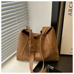 Detail of a brown suede tote bag with wide shoulder strap and gold-tone metal buckle