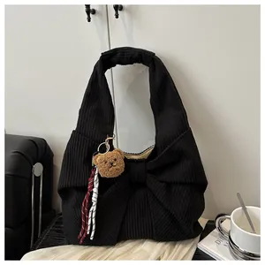 Gros plan du sac cabas en velours noir avec un grand nœud et un pendentif d'ours