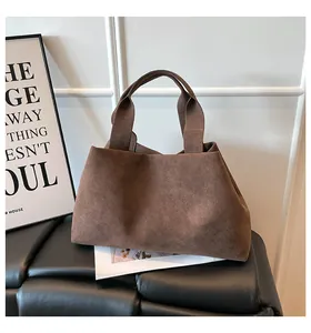 Detail of the brown suede-textured tote bag showing its vintage matte finish and wide handles