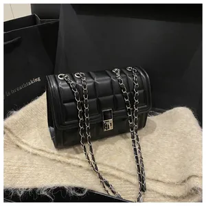 Macro shot of black quilted faux leather handbag with silver twist lock on plush background