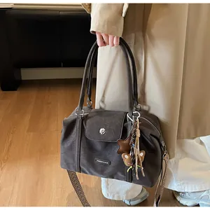 Detail of dark gray Boston bag with textured leather, woven strap and cute charms