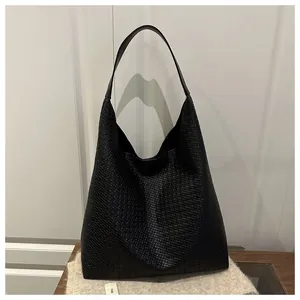 Détail d'un sac cabas noir en cuir tressé avec texture précise et large bandoulière