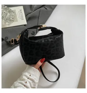 Detail of black leopard print crossbody bag on grey blazer with luxury accessories