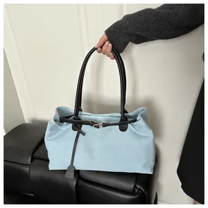 Detail of light blue denim tote bag with black leather handles and gold metal buckle
