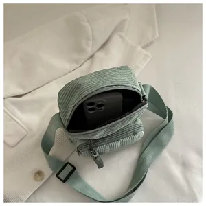 Gros plan du sac bandoulière en velours côtelé menthe avec compartiments et espace téléphone