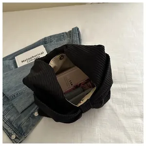 Détail d'un sac à bandoulière en velours côtelé noir avec fermoir aimanté et intérieur
