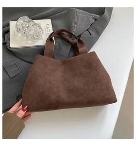 Close-up of minimalist dark brown suede tote bag on grey suit and art book background