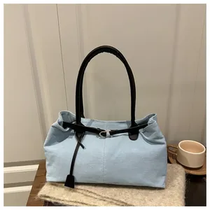 Detail of light blue canvas tote bag with black leather handles and silver buckle