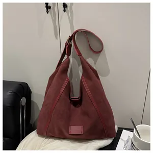 Detail of burgundy suede tote bag featuring adjustable wide strap and metallic buckle