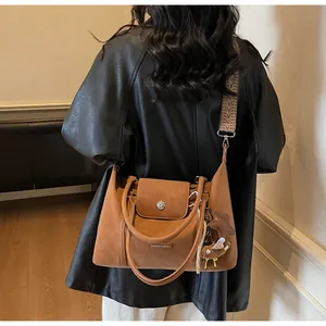 Brown pillow bag with vintage patterned strap and bear charm worn by a model