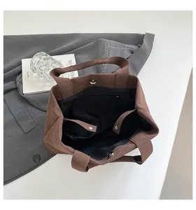 Top view of brown suede bucket bag with magnetic closure and inner zipper pocket detail