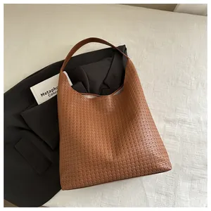 Gros plan sur la texture tressée marron et la large bandoulière du sac hobo