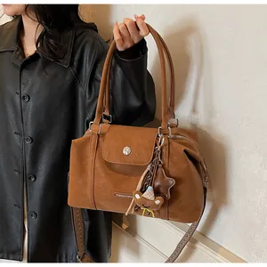 Detail of brown Boston handbag with textured wide strap and cute bear charm pendant