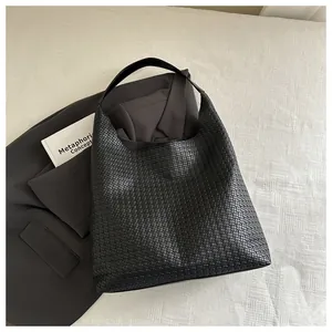 Détail du cuir tressé noir et de la bandoulière intégrée de ce sac hobo chic pour femme