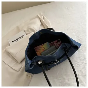 Internal view of large capacity denim blue tote bag showing black lining and white stitching