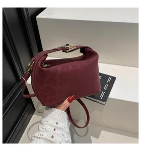 Detail of burgundy leopard embossed handbag with gold clasp and detachable shoulder strap